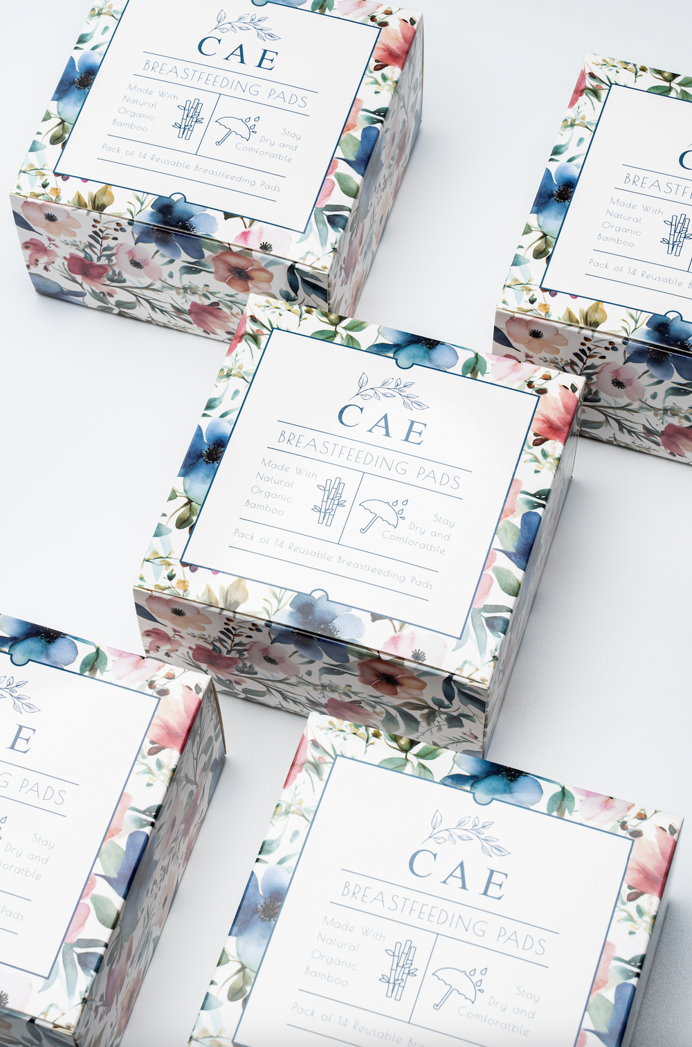 Several boxes of CAE reusable bamboo nursing pads with floral packaging